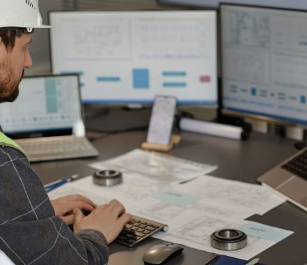 side-view-male-engineer-wearing-hardhat-workplace-office-using-computer-designing-blueprints-copy-space